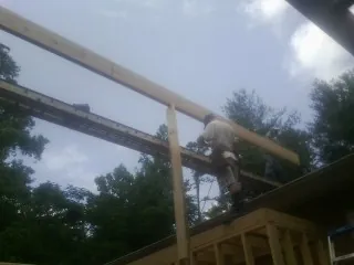 Carpenter setting a ridge beam over a new addition frame — Ice Dam Removal by Roofing Brothers in Bessemer City