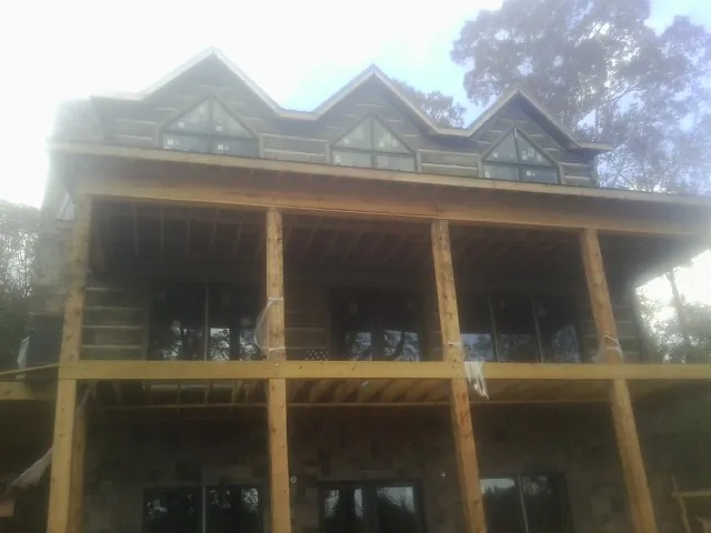 Dormers and porch framing on a large log home under construction — Roof Coating work by our crew in Bessemer City
