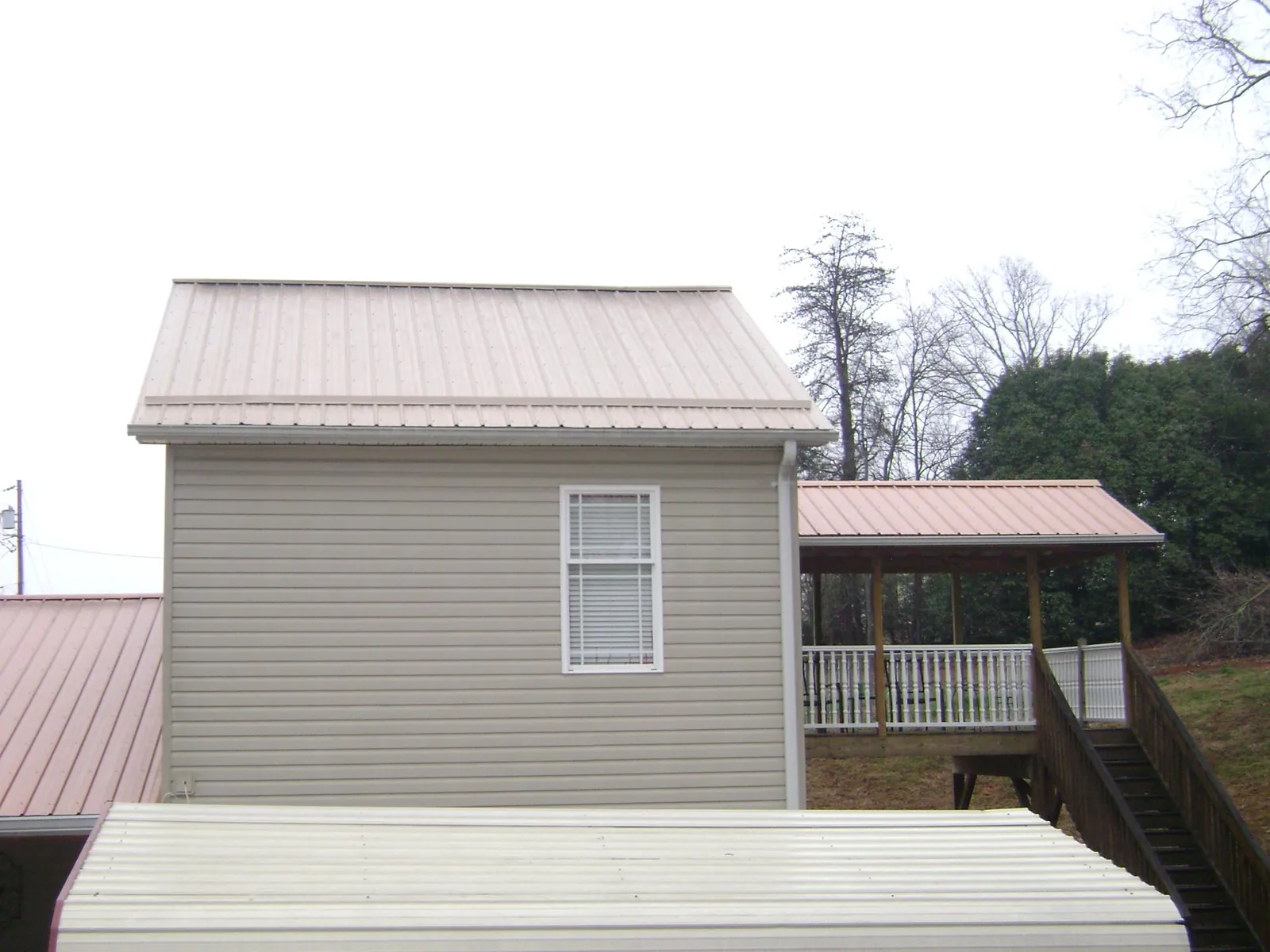 Tan metal roofs on a two story addition and attached porch, from a Roof Replacement job in Bessemer City