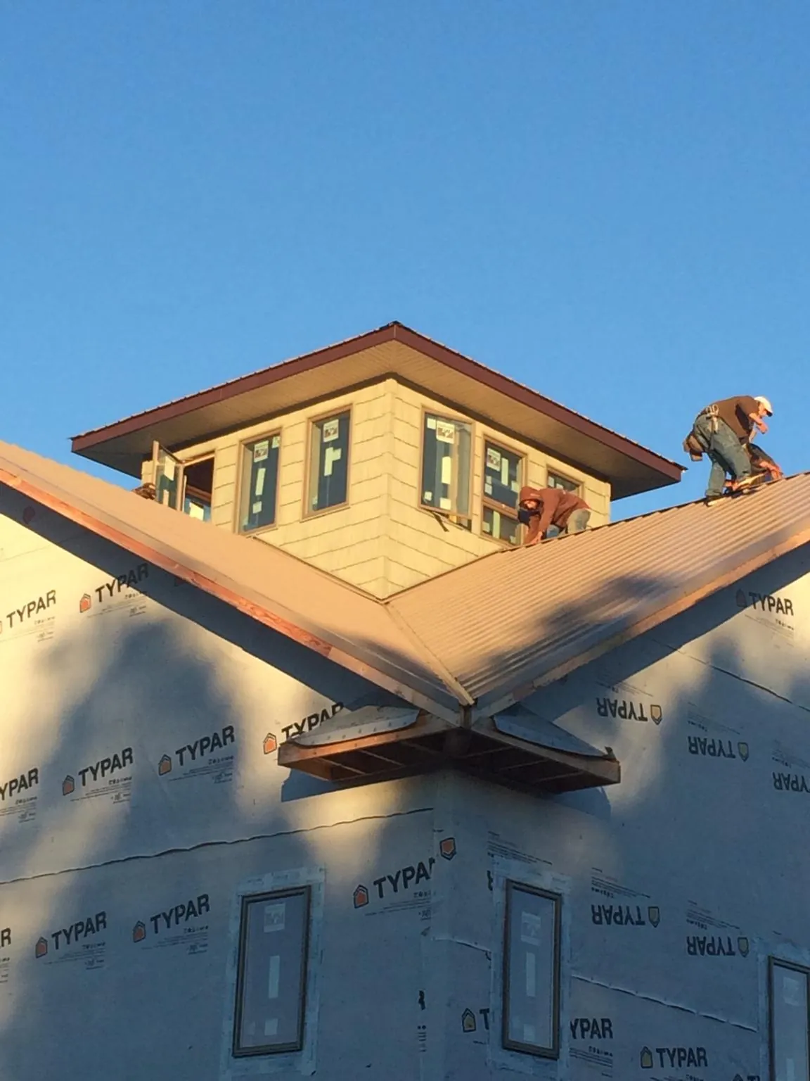 Roofers working around a rooftop cupola on a new metal roof at sunset — Roof Waterproofing in Bessemer City by Roofing Brothers